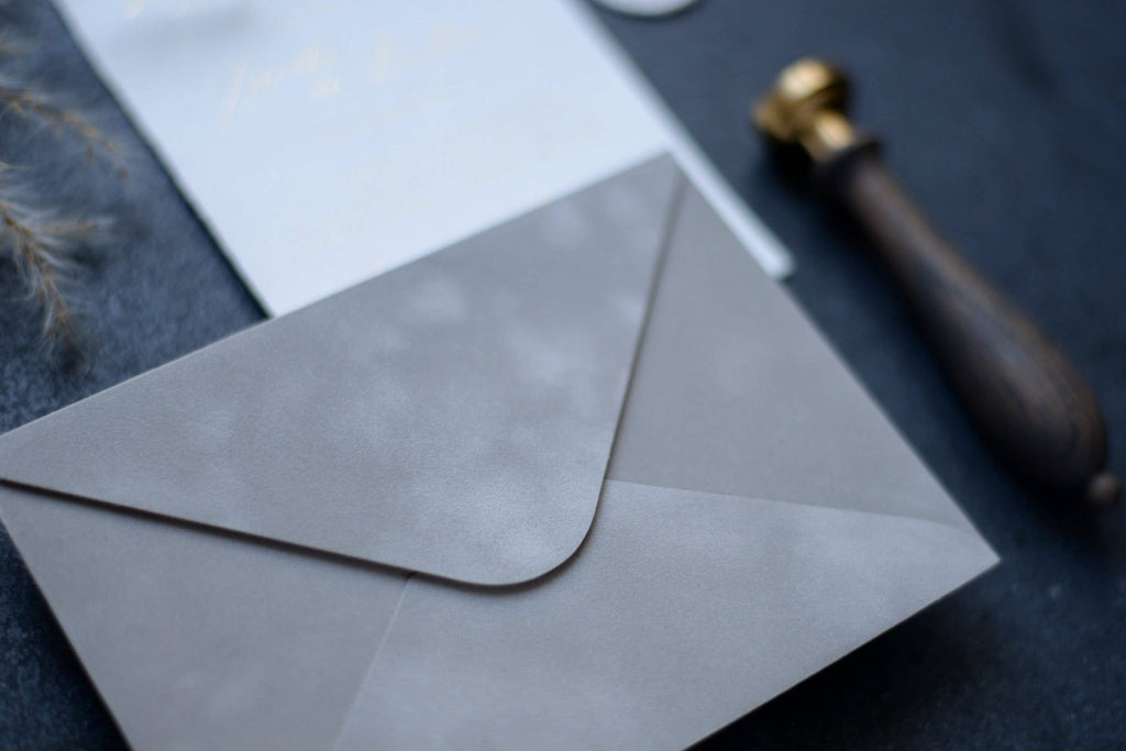 Close-up of a light grey velvet paper envelope with elegant stationery