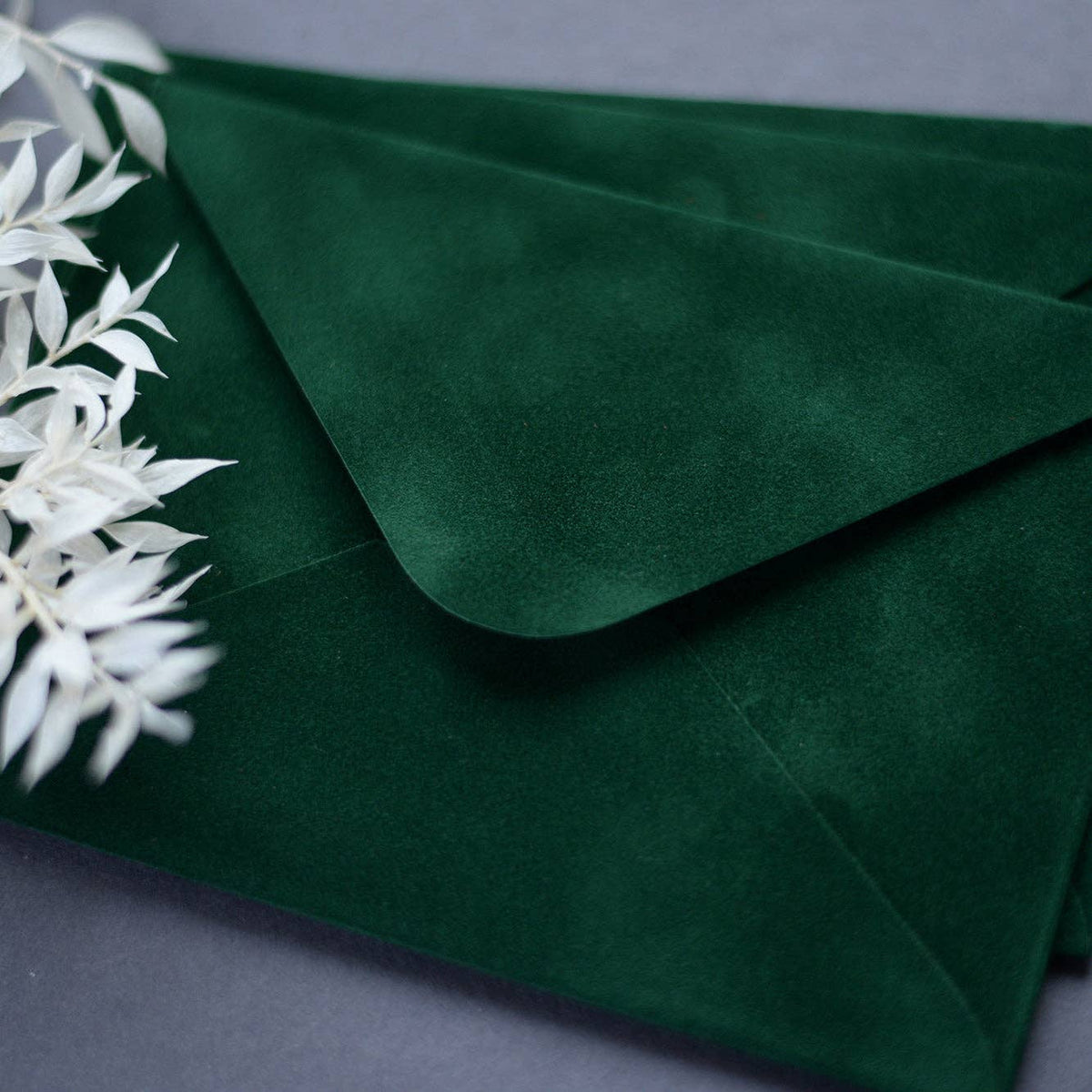 Close-up of a dark green velvet paper envelope showing its soft textured surface