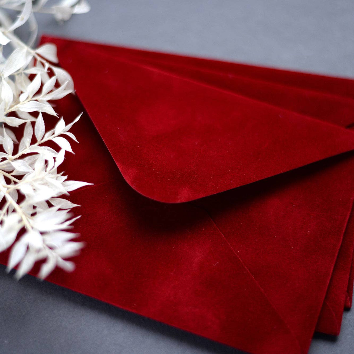 Close-up of a royal red velvet paper envelope showing its soft textured surface